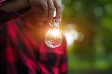 Man Holding Glowing Light Bulb outdoors © aekachai