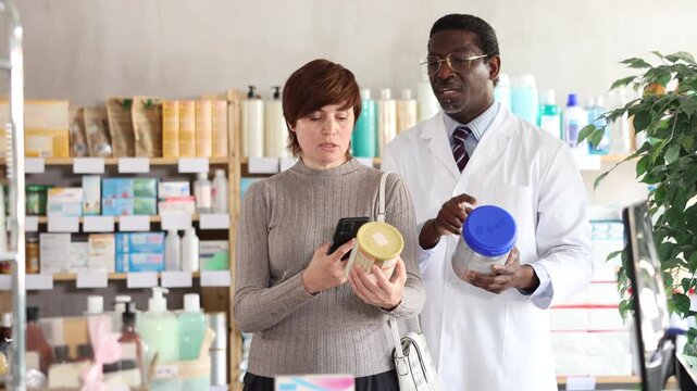 Adult woman buyer scanning qr code for baby formula with adult man pharmacist in pharmacy 
