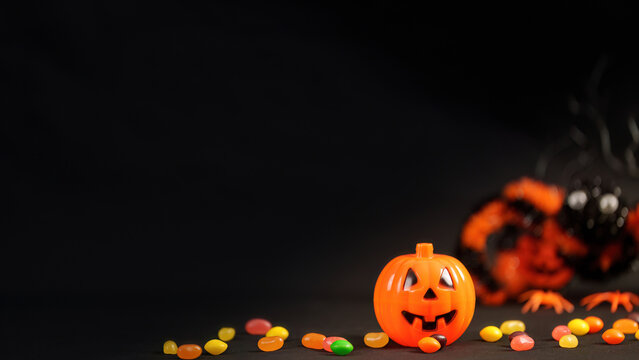 Halloween trick or treat concept with jack o lantern pumpkin and candy on dark background
