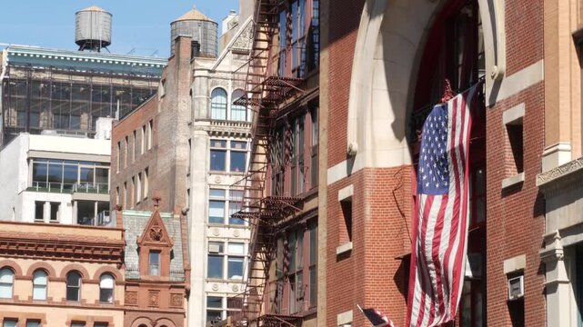 New York City classic Manhattan historic building architecture 1899, United States. Red brick house, USA american flag. Firehouse or fire station on Great Jones Street. Water tower tank, fire ladder.