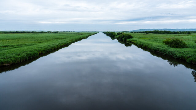 Long calm canal dividing the green marshes of Kiritappu Wetland in Hokkaido