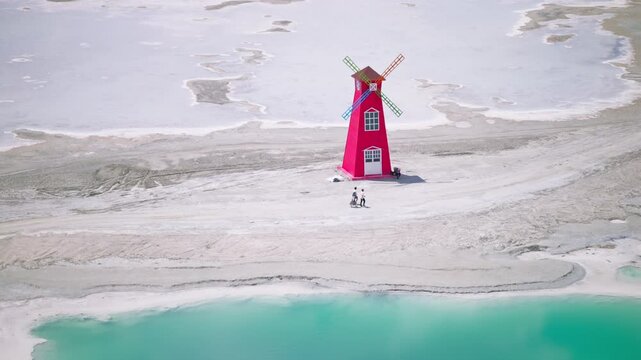 Aerial Panoramic View of Red Windmill Landmark in Dachaidan Emerald Lake: Colorful Salt Ponds, White Salt Crust and Azure Water in Qinghai