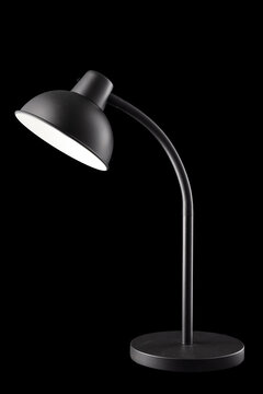 Modern black desk lamp turned on isolated on black background, vertical
