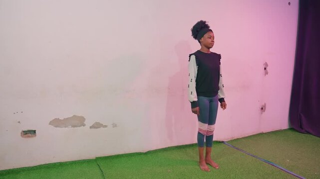Child tests balance. Child in casual jeans tests stance. Young boy stands barefoot testing equilibrium posture. Child in jeans balances carefully on grassy mat observing surroundings