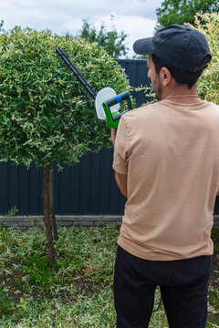 A gardener trims bushes. Selective focus.