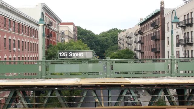 New York City Upper Manhattan subway outdoor station platform, 125 street sign, elevated metro in Harlem, United States railway. Residential district public metropolitan transport. Apartment houses.