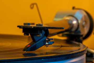 A close-up image showing the turntable needle as it plays a vinyl record, presenting the depth, warmth, and rich sound of an analog audio experience. © alexander