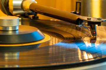 A close-up image showing the turntable needle as it plays a vinyl record, presenting the depth, warmth, and rich sound of an analog audio experience. © alexander