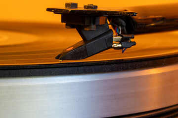 A close-up image showing the turntable needle as it plays a vinyl record, presenting the depth, warmth, and rich sound of an analog audio experience. © alexander