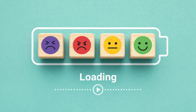 Four wooden cubes with emoticons representing emotions progress across a battery outline labeled 'Loading' in a clean studio setting