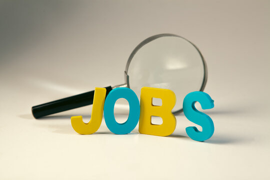Jobs word with magnifying glass on white background. Job search concept