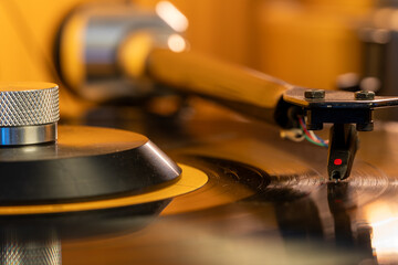 A close-up image showing the turntable needle as it plays a vinyl record, presenting the depth, warmth, and rich sound of an analog audio experience. © alexander
