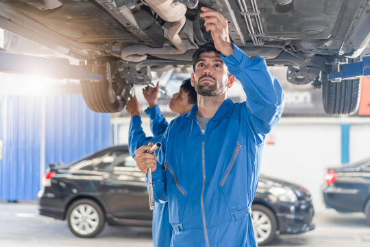 Auto check up and car service shop concept. Mechanic writing job checklist to clipboard to estimate repair quotation to client at workshop garage.