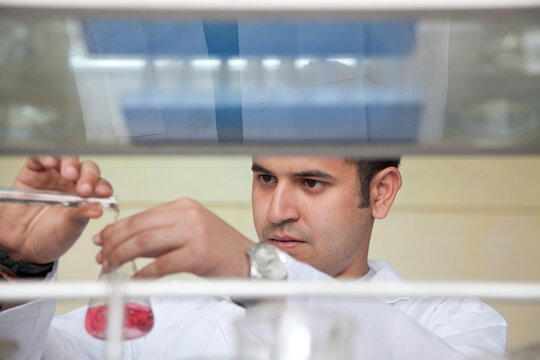 College student pouring liquid into beaker