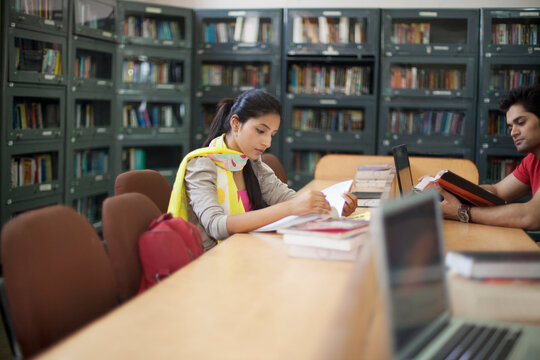 College student reading a book in library