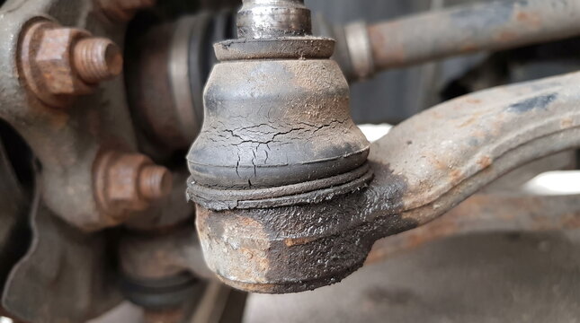 Close-up of worn automotive steering tie rod end with cracked rubber dust boot