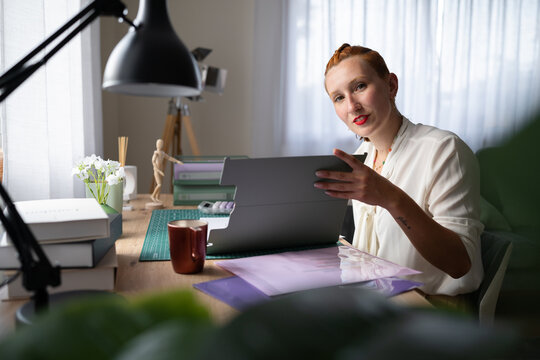 A white woman works from home using a tablet