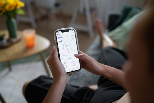 White Person adjusting home temperature with mobile app in living room