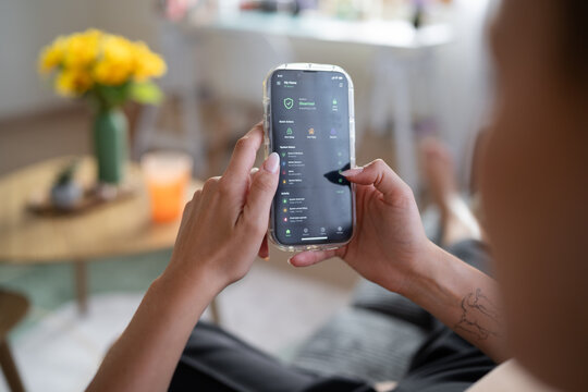 White Person monitors home security system remotely using smartphone