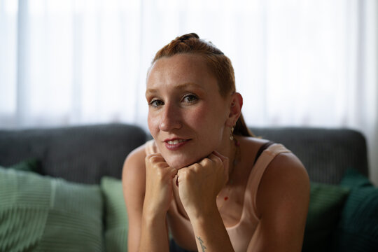 A white woman with red hair resting her chin on her hands