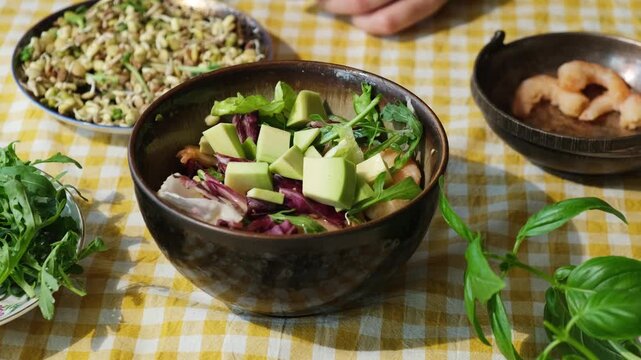 Preparing salad with shrimps and avocado. Female hand adding ingredients to summer salad. Healthy eating.