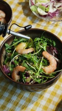 Vertical video. Heathy dinner or breakfast. Salad with shrimps, basil, arugula, lettuce and bean sprouts. Preparing summer salad pouring olive oil.