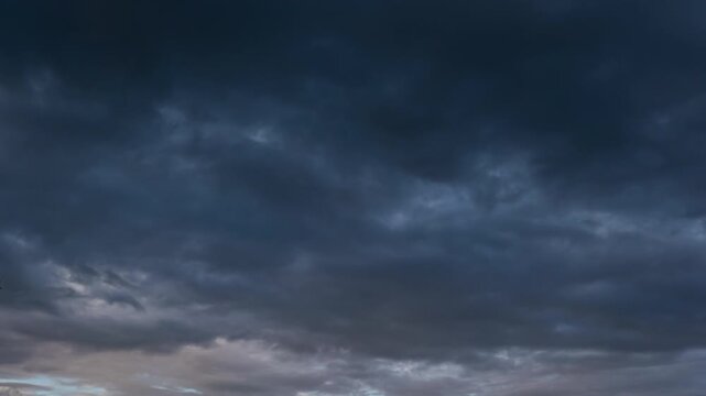 Ominous dark thunderclouds moving fast across the sky, impending rain storm time-lapse.