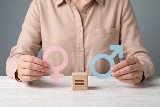 Person holding female and male gender symbols with an equality sign block
