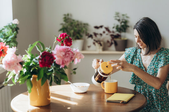 Woman pouring tea at home during a leisurely morning breakfast