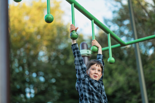 Boy climbs on an obstacle course at the playground in summer