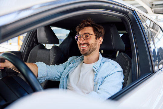 Cheerful driver smiling while driving a car during a test drive