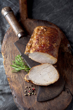 Sliced rolled roast pork on a vintage cleaver and wooden board