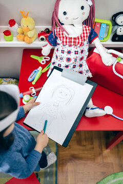 Top view of little girl drawing her doll