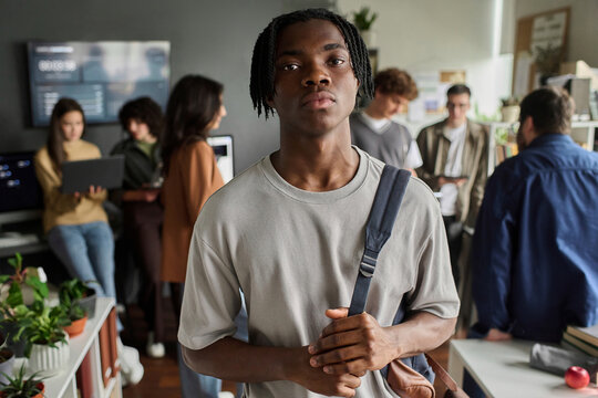 Confident young man stands in a university classroom with a group