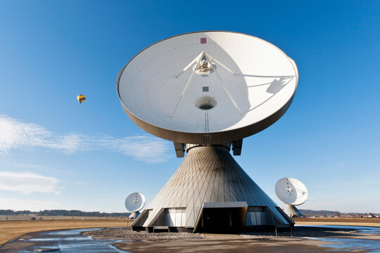 Germany, Bavaria, Raisting, View of antennas at earth station with hot air balloon in distance