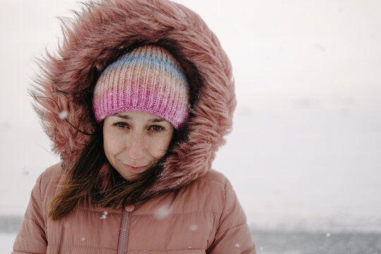 Woman wears pink winter jacket in snowy landscape of Lapland