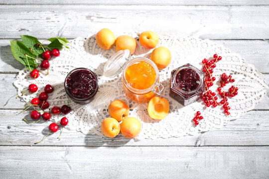 Cherry jam and cherries, Apricot jam and apricots, Currant jam and red currants on dolly