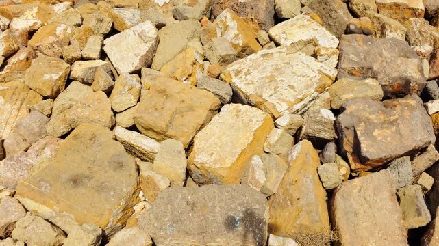 Large rough rocks and natural stone blocks in warm brown, beige and ochre tones. Irregular mineral surfaces with weathered texture. Geological rock background, rugged stone pattern and natural