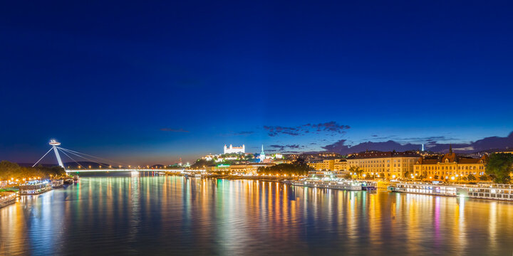 Slovakia, Bratislava, view to lighted castle and river cruise ships on the Danube in the foreground at night