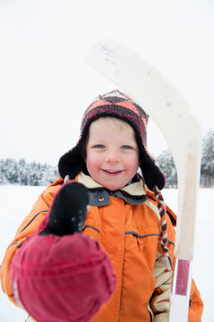 Italy, South Tyrol, Seiseralm, Boy (4-6) holding ice hockey stick, thumbs up, smiling, portrait, close-up