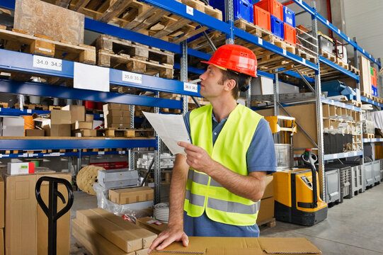 A warehouse worker in Bavaria conducts inventory checks with a clipboard in hand at a Munich warehouse