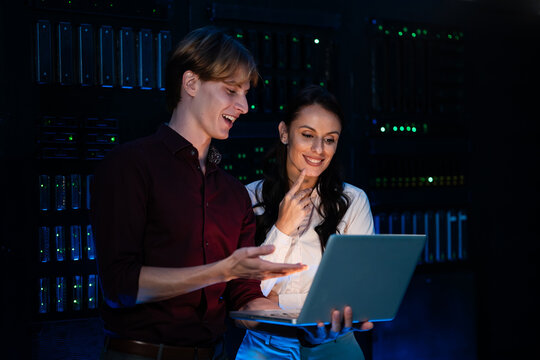 It professionals analyzing data on laptop in server room