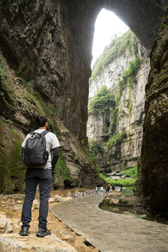 Man is tourist to see view of a huge cave hole scenery at Tianlong Bridge, the first natural stone bridge of Three Natural Bridges in Wulong Karst National Geology Park, a UNESCO World Heritage Site i