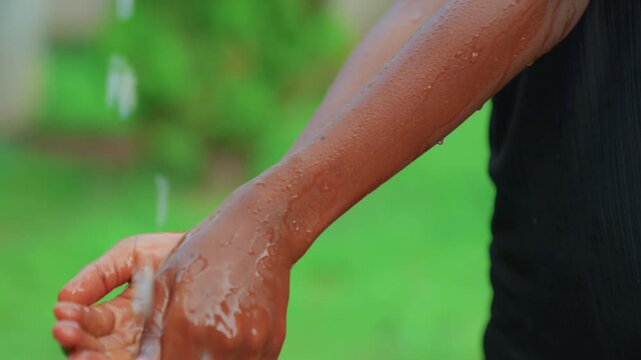 Streams of droplets cleanse skin softly. Hands and forearms under running water with soothing motion. Gentle rinse of hands and forearms with streams of water on natural background