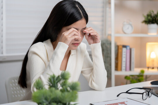 Eye problems, Asian women with tired and irritated eyes, eye rubbing, dry, eye pain after work, migraine, headache, blurred vision, photophobia, working in the dark, blue light from computer