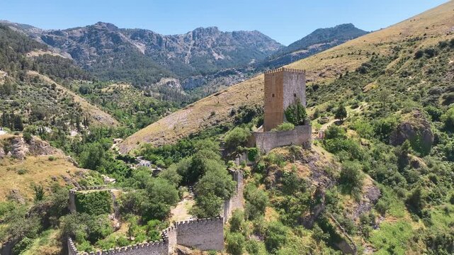 Aerial flies close around the curtain walls and battlements of Jaen's famous Castillo de la Yedra in Cazorla at the base of the mountains. Spain.