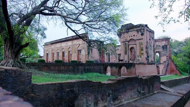 Wide shot of the historic Lucknow Residency captured in natural daylight. The frame highlights the colonial‑era ruins with weathered brick walls, arched openings, and lush greenery surrounding the sit