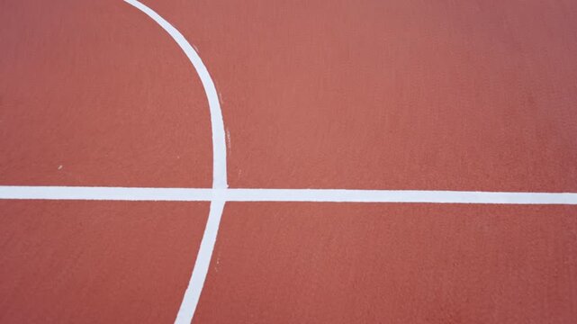 Neat markings divide red sports flooring on outdoor playground. Minimalist composition highlights quality of modern stadium infrastructure