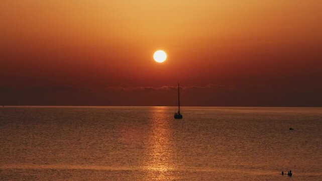Peaceful morning sunrise illuminating an anchored sailboat in Cala Mesquida