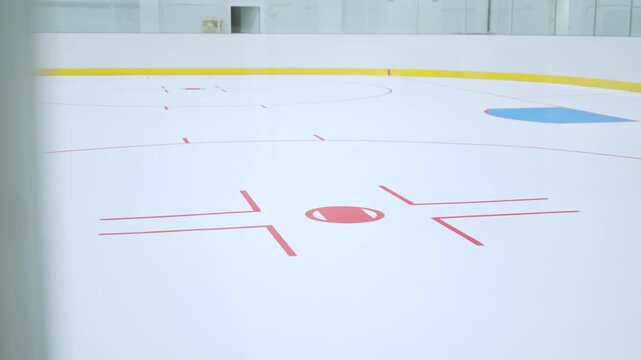 Clean indoor ice arena features painted lines and protective glass barrier. Silent surface promises exciting competition in empty stadium